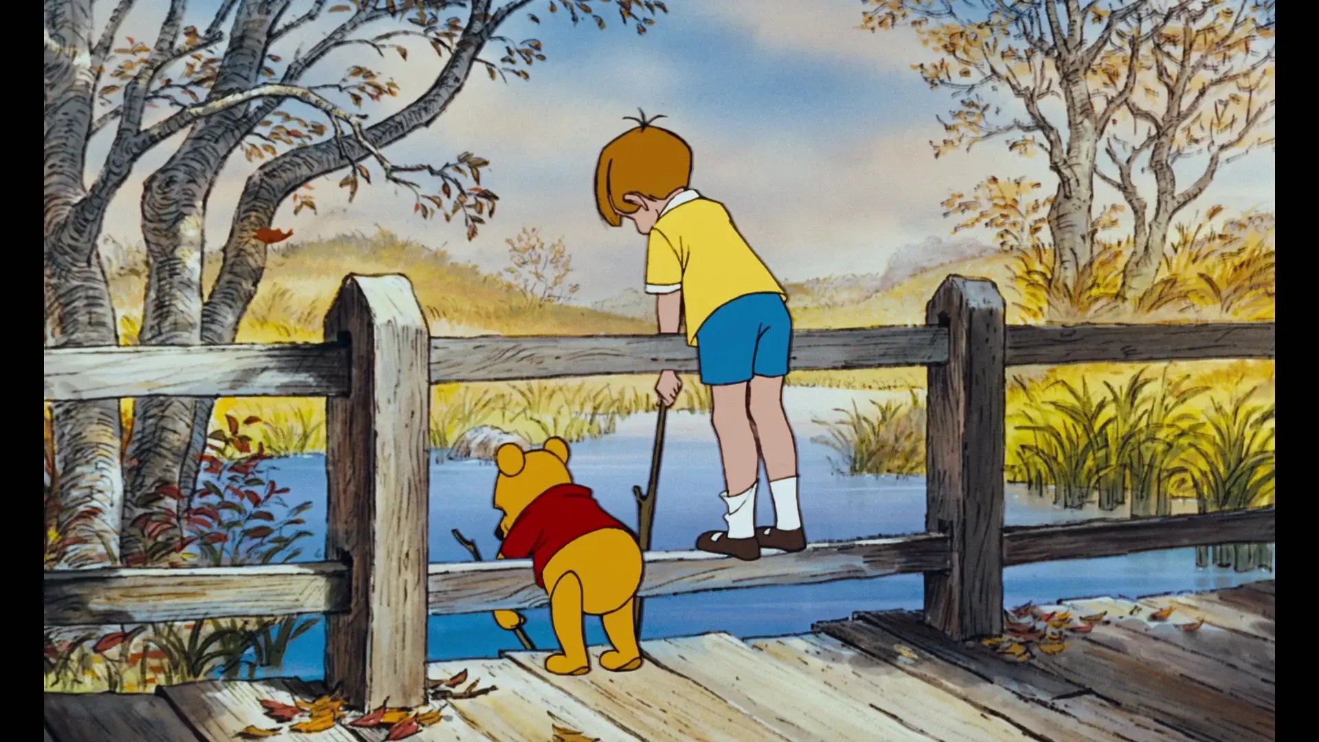Pooh and Christopher Robin holding sticks and looking over the bridge at the river