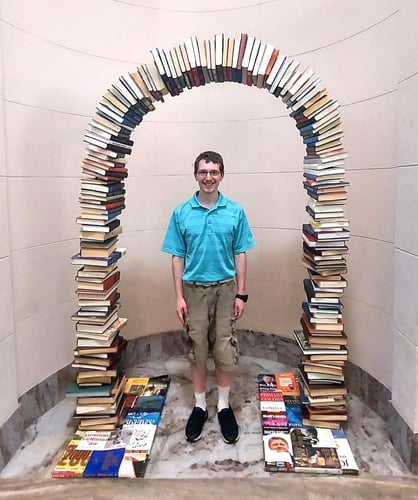 An arch of books with Nathan standing under it